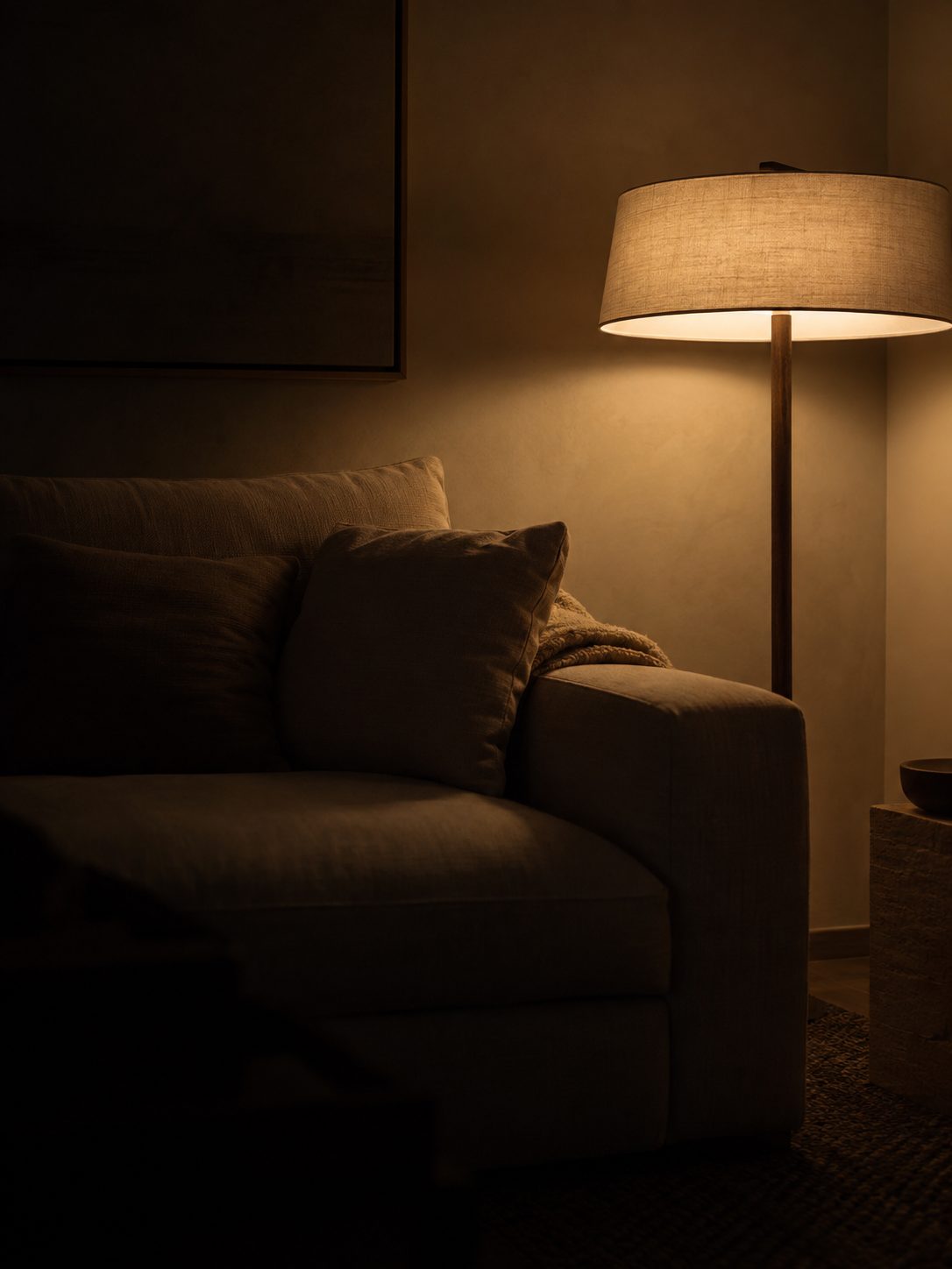 Lámpara de pie encendida junto a un sofá en un salón en penumbra